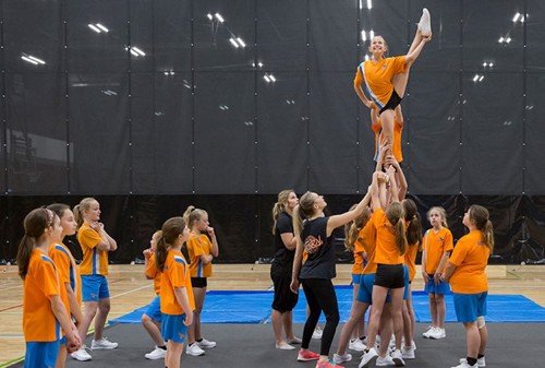 Rangatahi practicing cheerleading in an indoor space