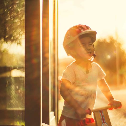 Helmeted smiling boy on wooden scooter image