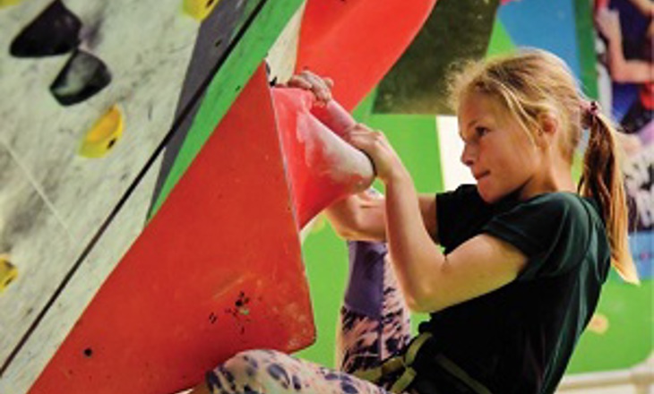 Girl scaling a climbing wall
