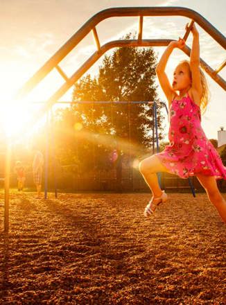 Girl having fun climbing on playground climbing bars