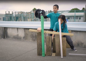 Boy and girl playing with large blocks of woods and pipes