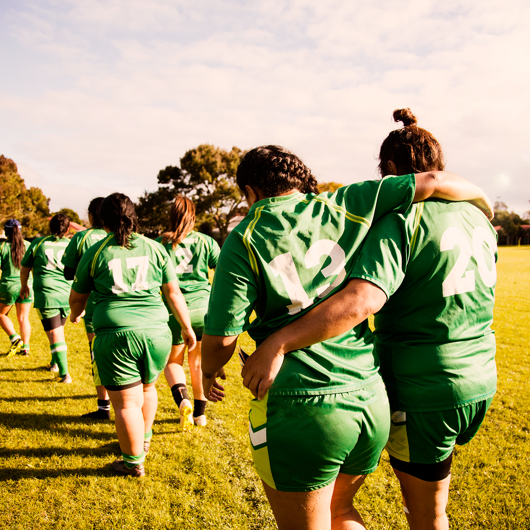 girls walking off a rugby field arms around each other  image