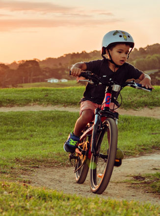 Tamariki in bike helmet biking on dirt track