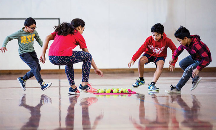 Kids/Tamariki grabbing balls from a hoop in a hall setting